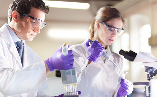 Two lab technicians working with a pipette